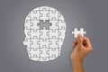 Hand inserting missing brain jigsaw in white man`s head shape Royalty Free Stock Photo