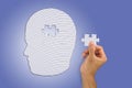 Hand inserting missing jigsaw in white man`s head shape Royalty Free Stock Photo