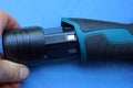 Hand inserts a black plastic battery into the handle of a screwdriver