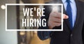 Hand interacting with weÃ¯Â¿Â½re hiring business text against blurred background