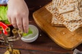 The hand of Jewish women dips maror in salt water at the Pesach Seder table