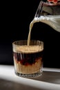 hand with jug pouring cream to glass of coffee