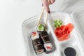 Hand keep roll with chopsticks, rolls, sushi. chopsticks, ginger, soy sauce in container delivery. Royalty Free Stock Photo