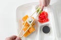 Hand keep roll with chopsticks, rolls, sushi. chopsticks, ginger, soy sauce in container delivery. Royalty Free Stock Photo