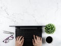 Hand on keypad laptop with glasses silver pen coffee cup flower vase on marble table workplace concept copy space top view Royalty Free Stock Photo