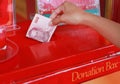 Hand of kid putting money for offertory in donation box