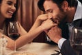 Hand, kissing and love with a couple in a restaurant on a date night out together for fine dining or luxury. Love