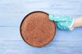 The hand in the kitchen mitten holds a shape with a baked chocolate biscuit on blue wooden background