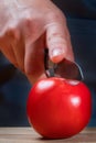 Hand with a knife cuts a round red fresh tomato, close-up. Royalty Free Stock Photo