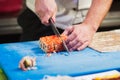 Hand with knife cuts sushi. Royalty Free Stock Photo