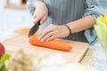 Hand with knife cutting carrot. Woman prepares food at table. Chef cooks delicious dinner. Work that requires skill Royalty Free Stock Photo