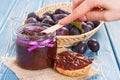 Hand with knife preparing fresh sandwiches with plum marmalade or jam, healthy sweet breakfast concept Royalty Free Stock Photo