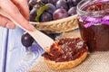 Hand with knife preparing fresh sandwiches with plum marmalade or jam, healthy sweet breakfast concept Royalty Free Stock Photo