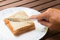 Hand with knife slicing wholemeal sandwich bread diagonally into two portions