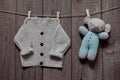 Hand knitted clothes and a toy for a newborn to hang on a clothespin on a rope on a wooden background, happy birthday card, baby b