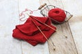 Hand knitted red scarf, yarn ball and knitting needles