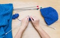 Hand knitting with knitting needles. A woman knits at a wooden t