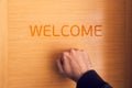 Hand knocking on door with welcome sign Royalty Free Stock Photo