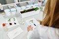 hand of lab worker measure length of green plant on table with equipment