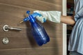 Hand of lady in white gloves that applying alcohol spray to cleaning and disinfection of the door handle. Actions to prevent the