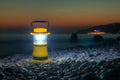 Hand lantern on pebble beach at dusk
