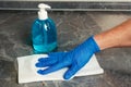 Hand in latex glove cleaning of kitchen table with paper towel and antiseptic liquid