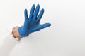 Hand in a latex glove showing a warning sign through torn white wall Royalty Free Stock Photo