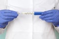 Hand in latex gloves holds a medical mercury thermometer