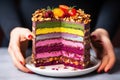 hand-layering a raw vegan rainbow cake with colorful fruit and nut layers