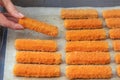 The hand lays out the fish fingers on the frying paper. The concept of frying fish sticks in the oven. Side view. Royalty Free Stock Photo