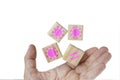 A hand and levitating wooden cubes embossed with pink viral symbols and needles icons