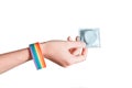 Hand with LGBT bracelet holding a condom