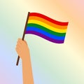 A hand with an LGBT flag on a gentle rainbow background. Pride month banner, poster, background.