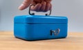 Hand lifts a blue cash box