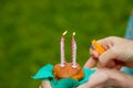 Hand with a lighter to light the candle blueberry muffins on green background. burning four candles on Birthday cupcake Royalty Free Stock Photo