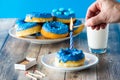 A hand lighting a candle on a blue chocolate candy dipped donut.