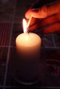 Hand lighting candle with burning flame. Christmas holiday decoration. Romantic love valentine`s day mood.