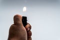 Hand lighting a cigarette lighter on a gray background