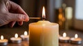 Hand lighting a large candle with a match surrounded by tea lights Royalty Free Stock Photo