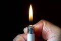 A hand lighting up a lighter with flame and dark background. Royalty Free Stock Photo