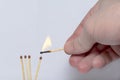 Hand with a lit match ignites matches.