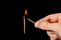 A hand with a lit match sets fire to a new match Royalty Free Stock Photo