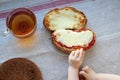 The hand of a little boy who is trying to steal my father`s sandwich with tea. Royalty Free Stock Photo