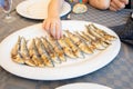 Hand of little child taking sardines in a row cooked in a big white dish