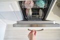 Hand loading dishwasher with dishes in open kitchen appliance interior view Royalty Free Stock Photo