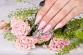 Hand with long artificial green french manicured nails and pink rose flowers