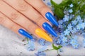 Hand with long artificial manicured nails colored with blue and orange nail polish Royalty Free Stock Photo