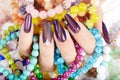 Hand with long artificial manicured nails holding colorful bracelets Royalty Free Stock Photo