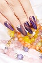 Hand with long artificial manicured nails holding a necklace Royalty Free Stock Photo