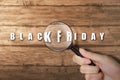 Hand looking at Black Friday text with magnifying glass Royalty Free Stock Photo